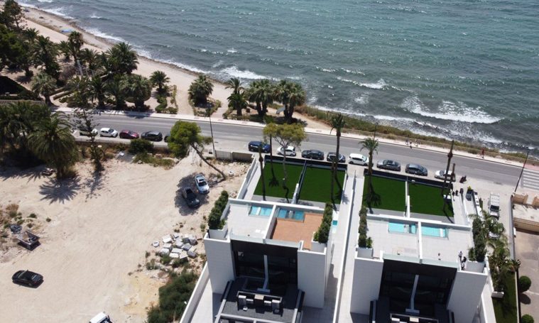 Venta de solar donde NEXUS Promotores construirán 16 Chalets de lujo frente al mar Vistas aéreas de casas modernas frente a la playa y el mar.